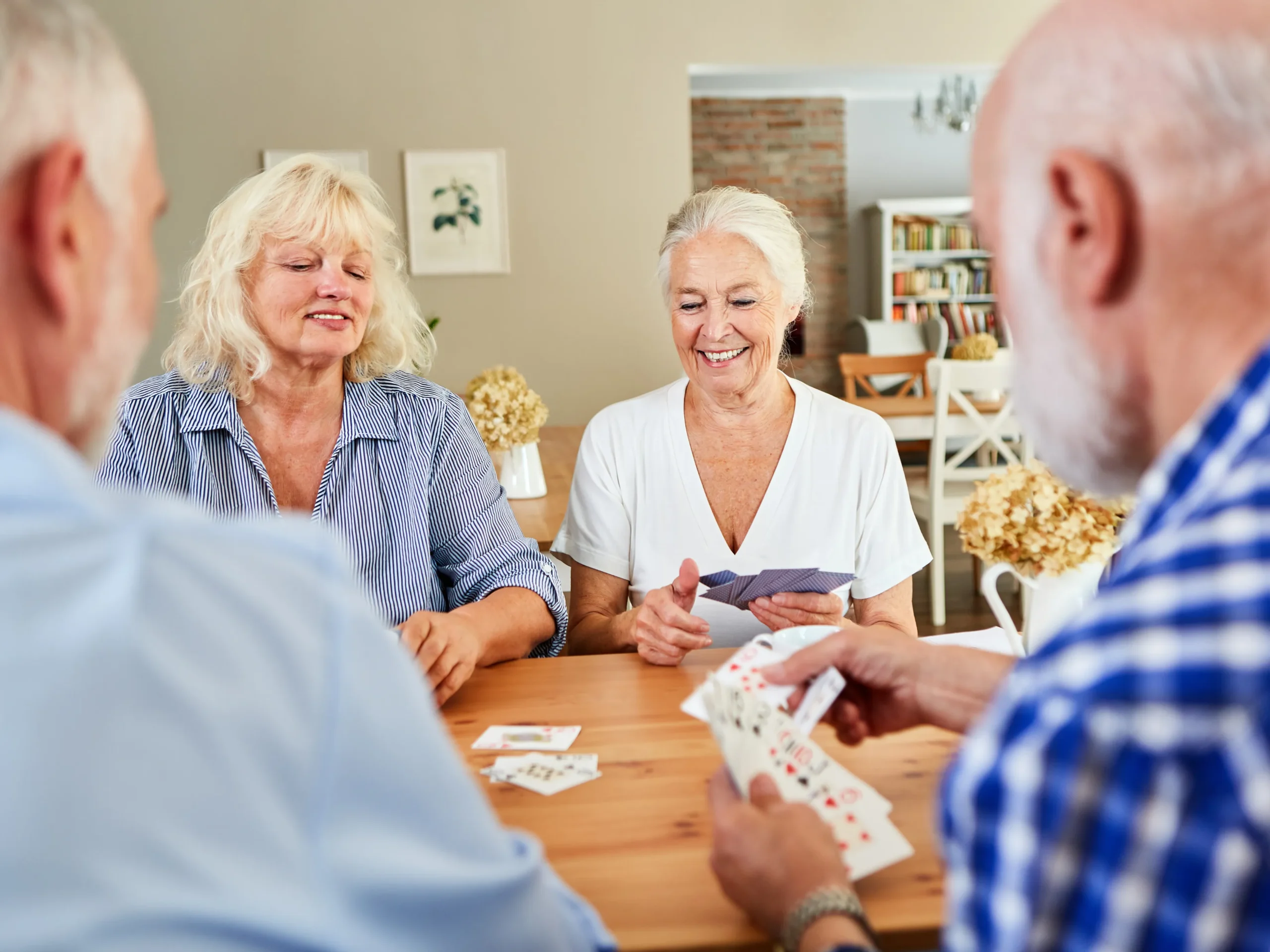 elderly friend group smiling and playing cards