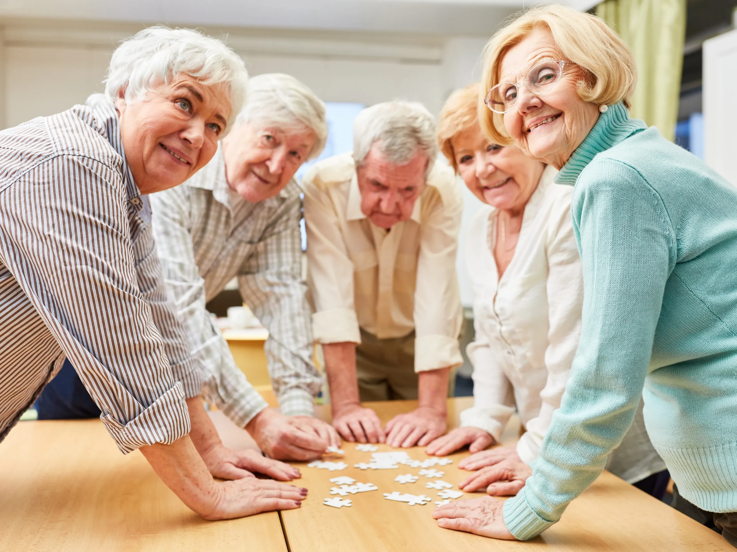 group of elderly friends playing memory games for seniors together- smiling