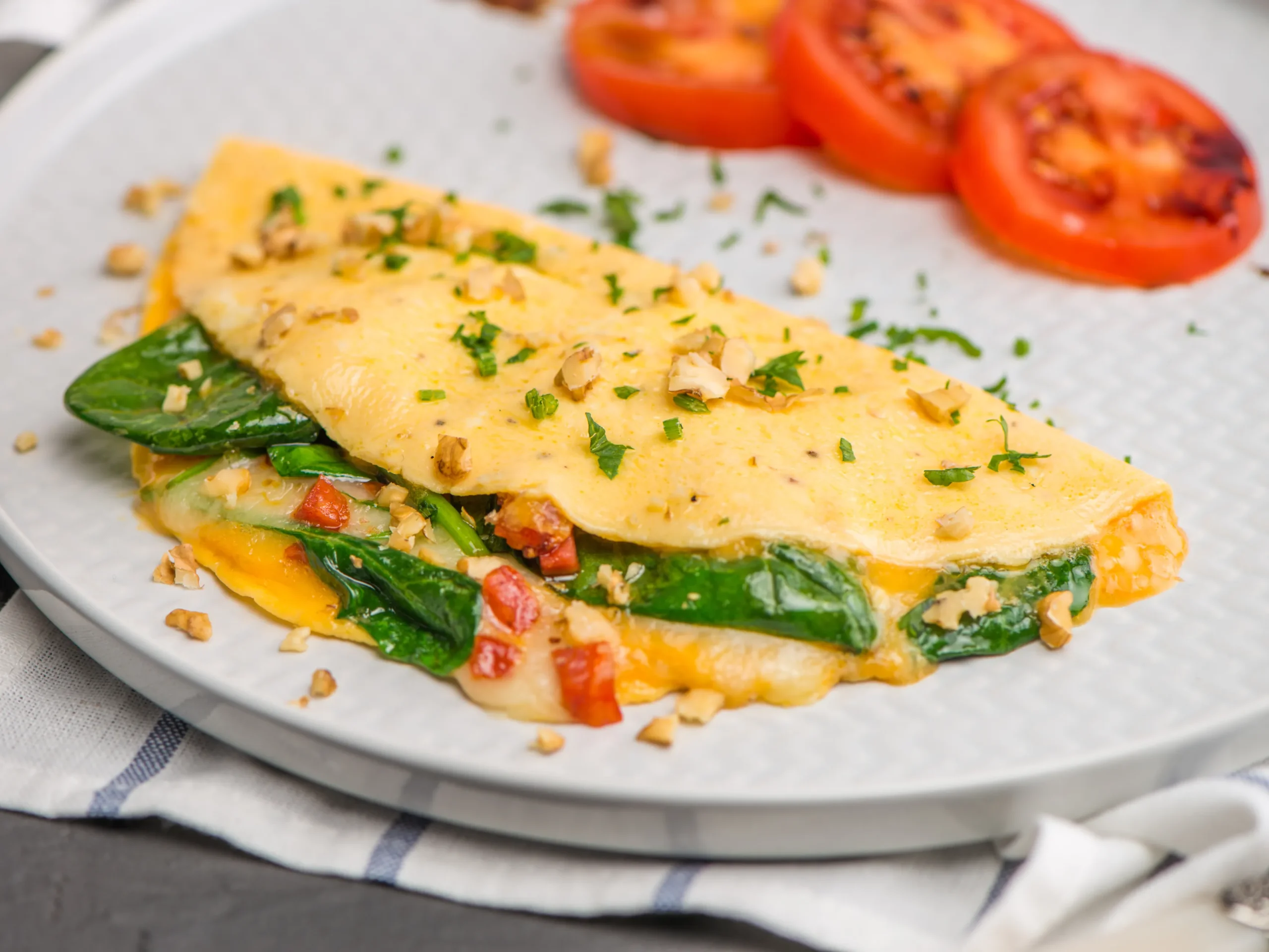 omelet with cheese and spinach on a plate with tomatoes